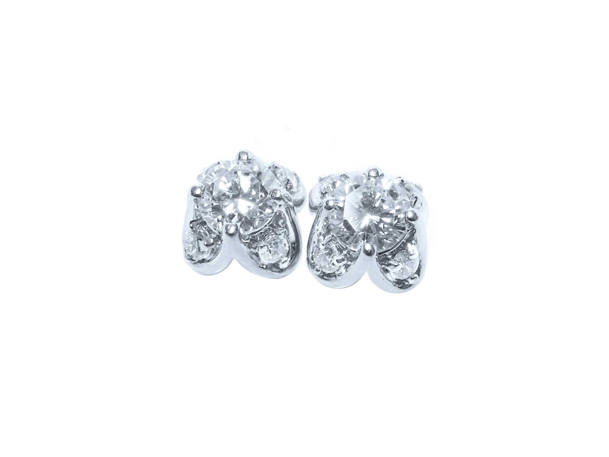 A pair of white gold diamond stud earrings with a round cut and tulip prong set style, featuring accent diamond petals.