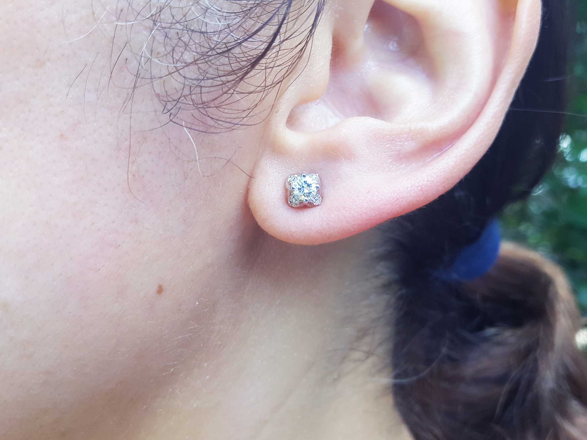 A woman&#39;s ear wearing a natural diamond tulip stud earring in white gold.
