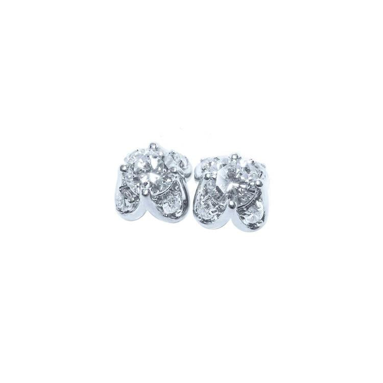 A pair of white gold diamond stud earrings with a round cut and tulip prong set style, featuring accent diamond petals.