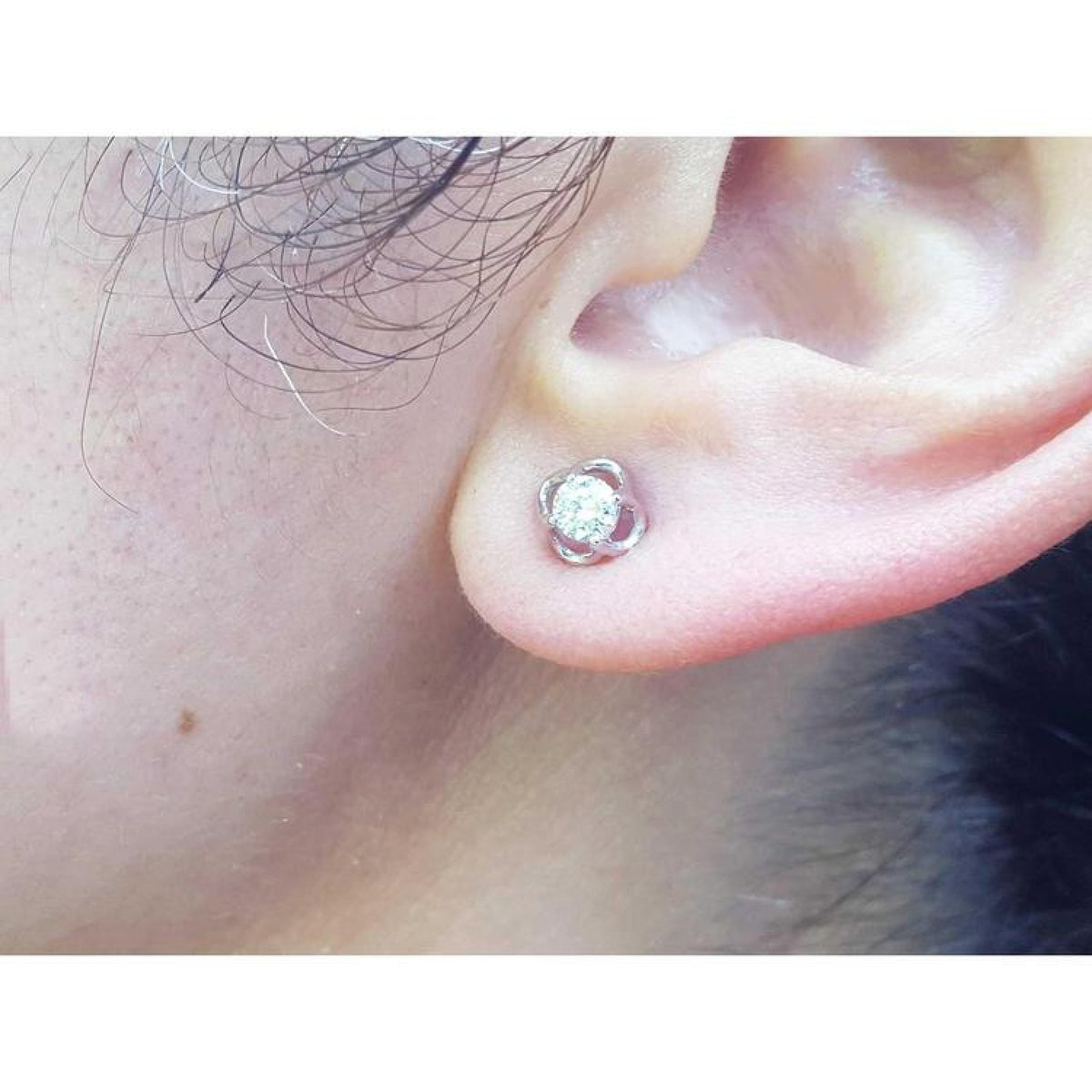 An earlobe wearing a bride's diamond tulip earring in white gold.