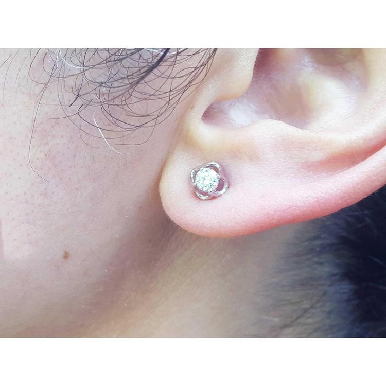 An earlobe wearing a bride's diamond tulip earring in white gold.