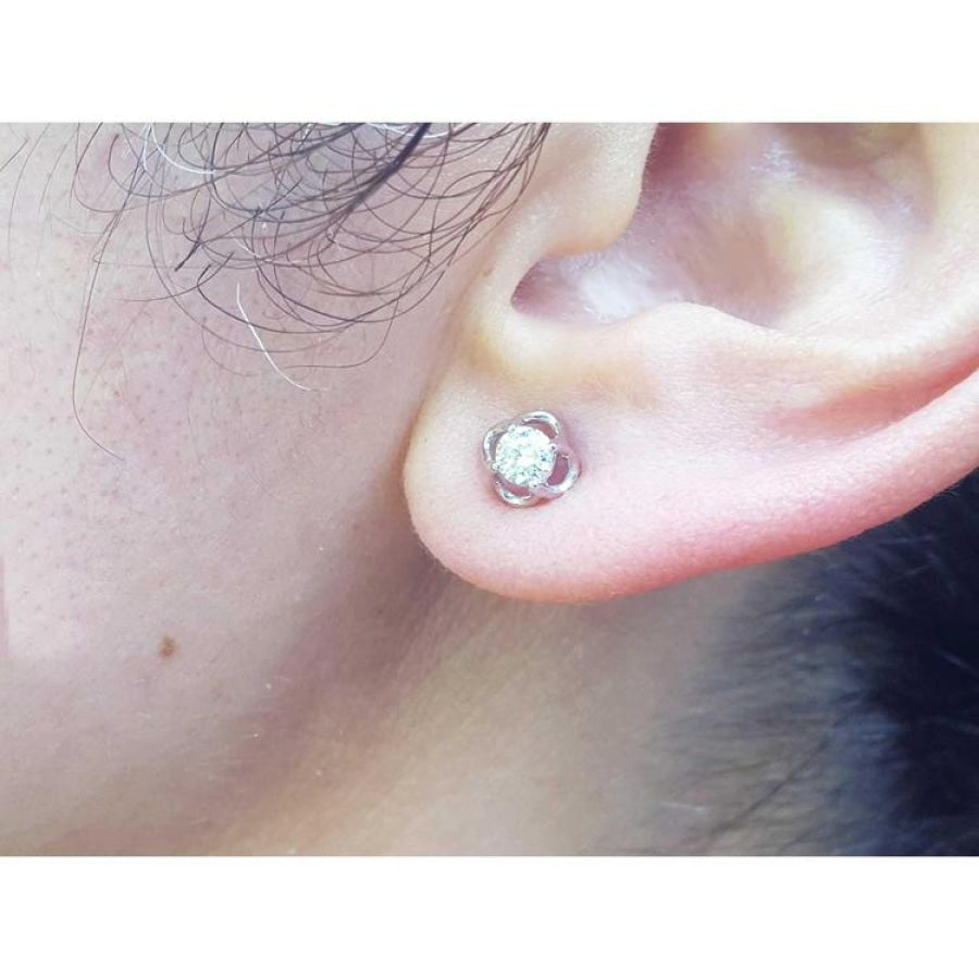An earlobe wearing a bride's diamond tulip earring in white gold.