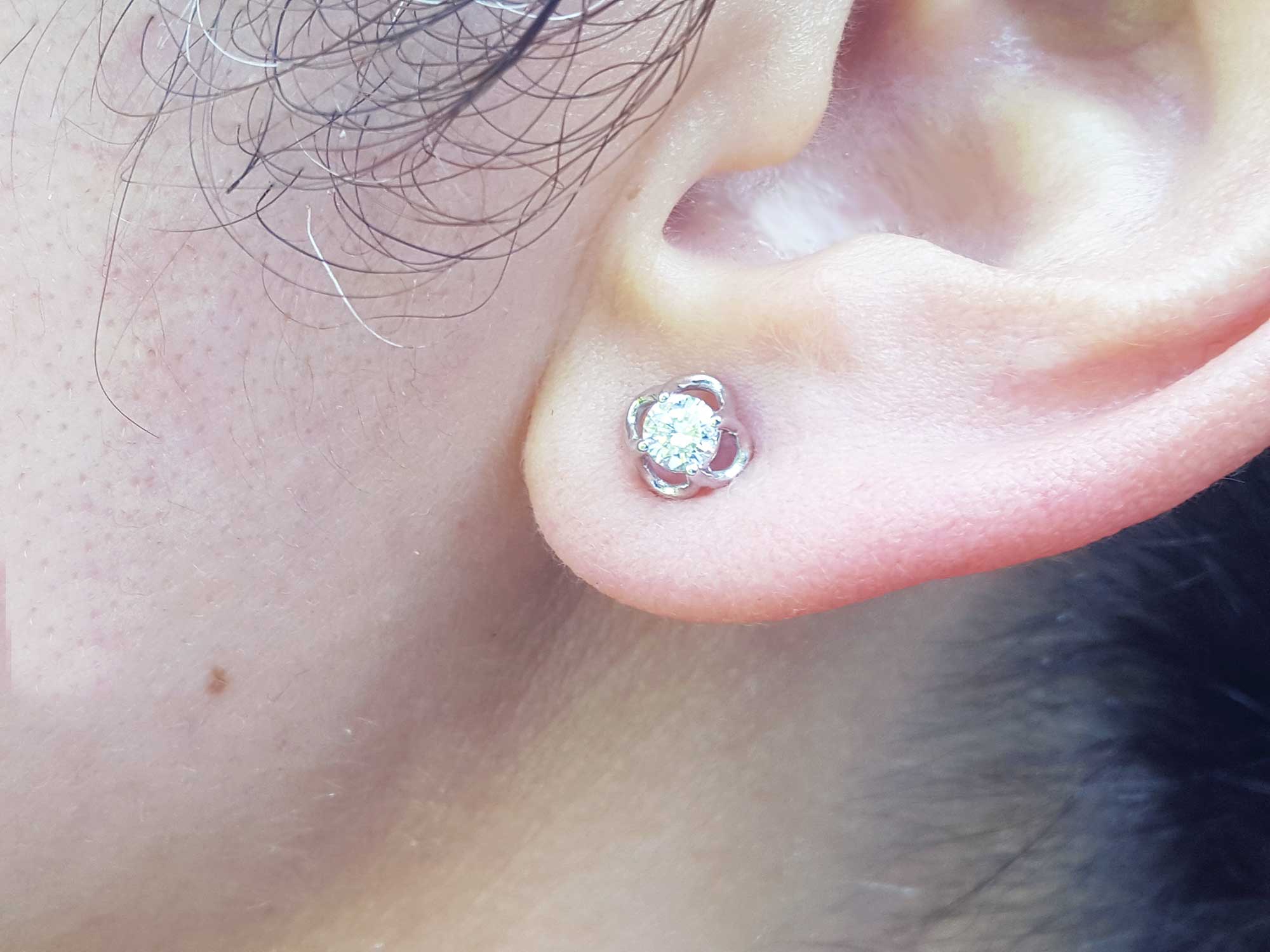 An earlobe wearing a bride's diamond tulip earring in white gold.