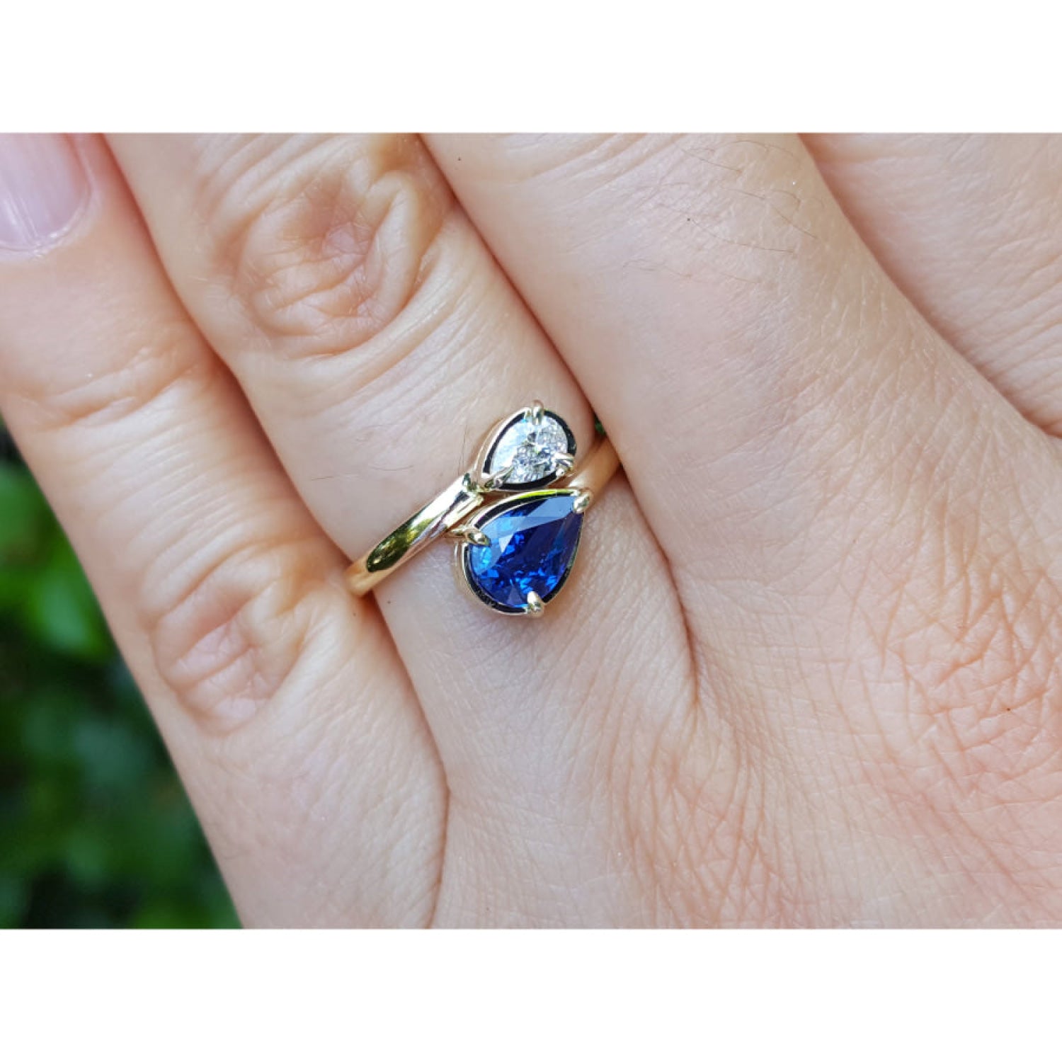 Two-stone "You and Me" blue natural sapphire bypass ring with a teardrop diamond on the side, handcrafted in 18k yellow gold.