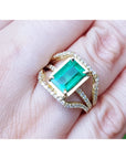 Toma grafica cercana de una mano exhibiendo un anillo de oro amarillo con esmeralda rectangular y diamantes laterales.