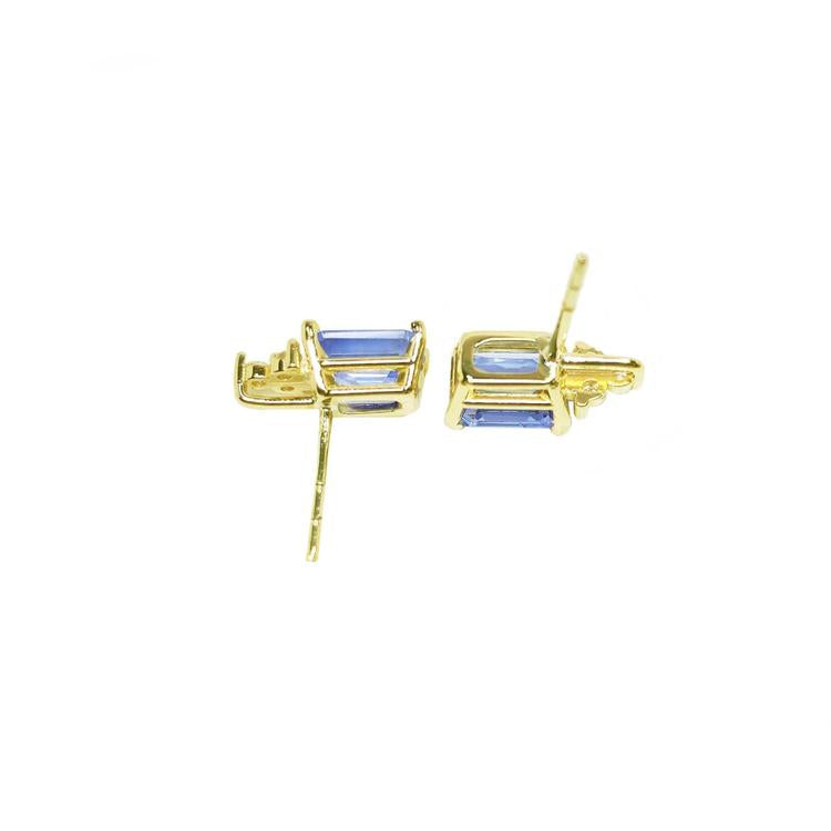 Gold earrings with blue gemstones on a upside down view position.