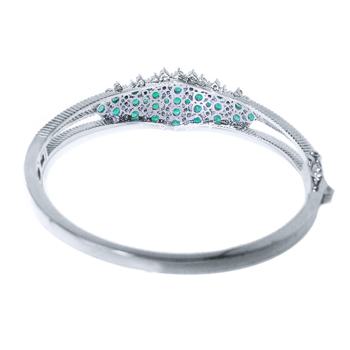 A white gold emerald bangle bracelet displaying its underside view.