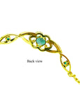 The downside view of a gold bracelet with genuine emeralds on a white background.
