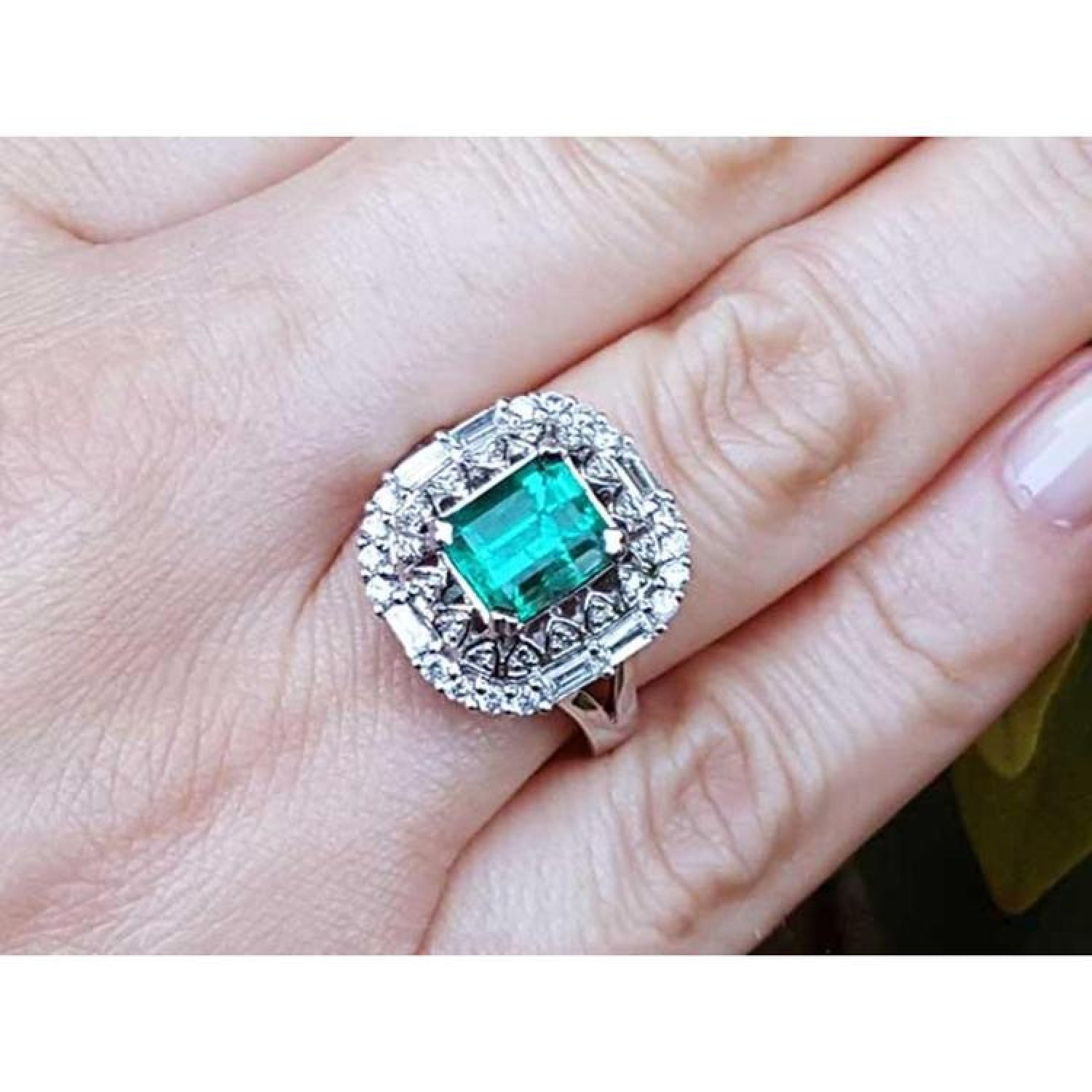 Vintage 2.40 ct Colombian emerald ring in 14K white gold with diamond accents on a hand.