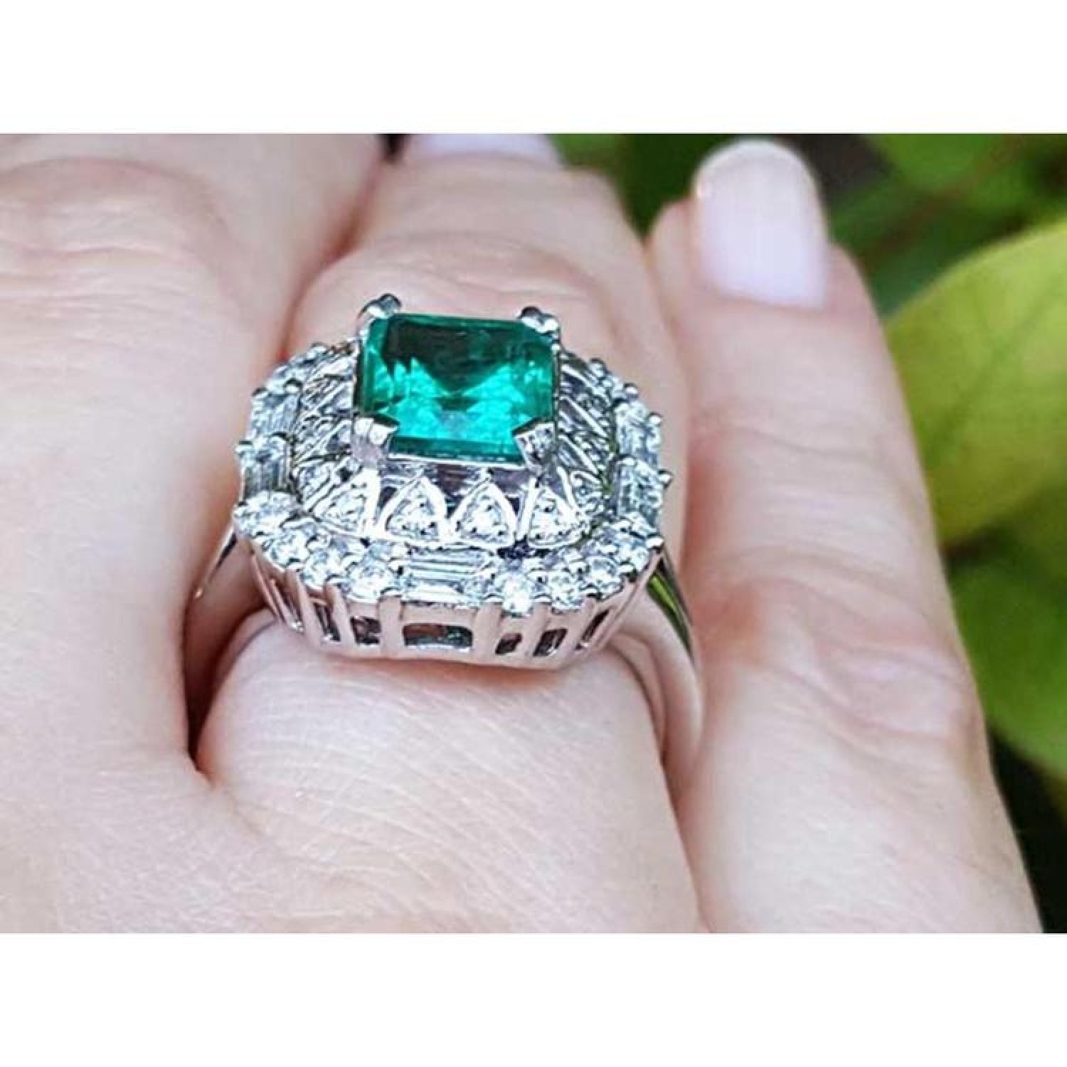 Vintage 2.40 ct Colombian emerald ring in 14K white gold with diamond accents on a finger.