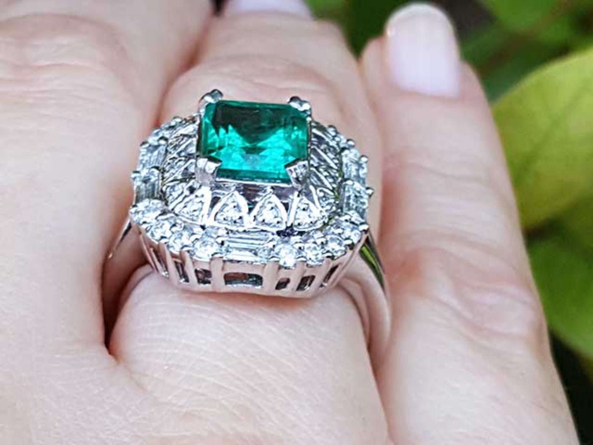 Vintage ring with a colombian emerald and diamond accents on a finger.