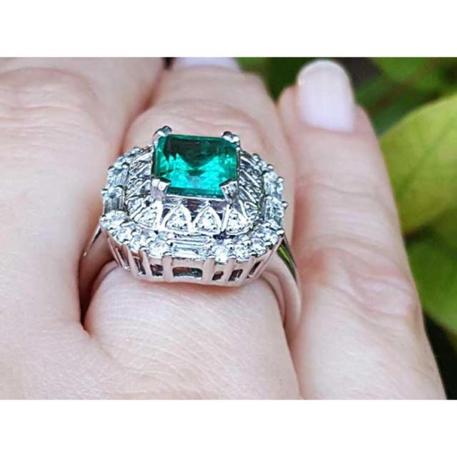 Vintage 2.40 ct Colombian emerald ring in 14K white gold with diamond accents on a finger.