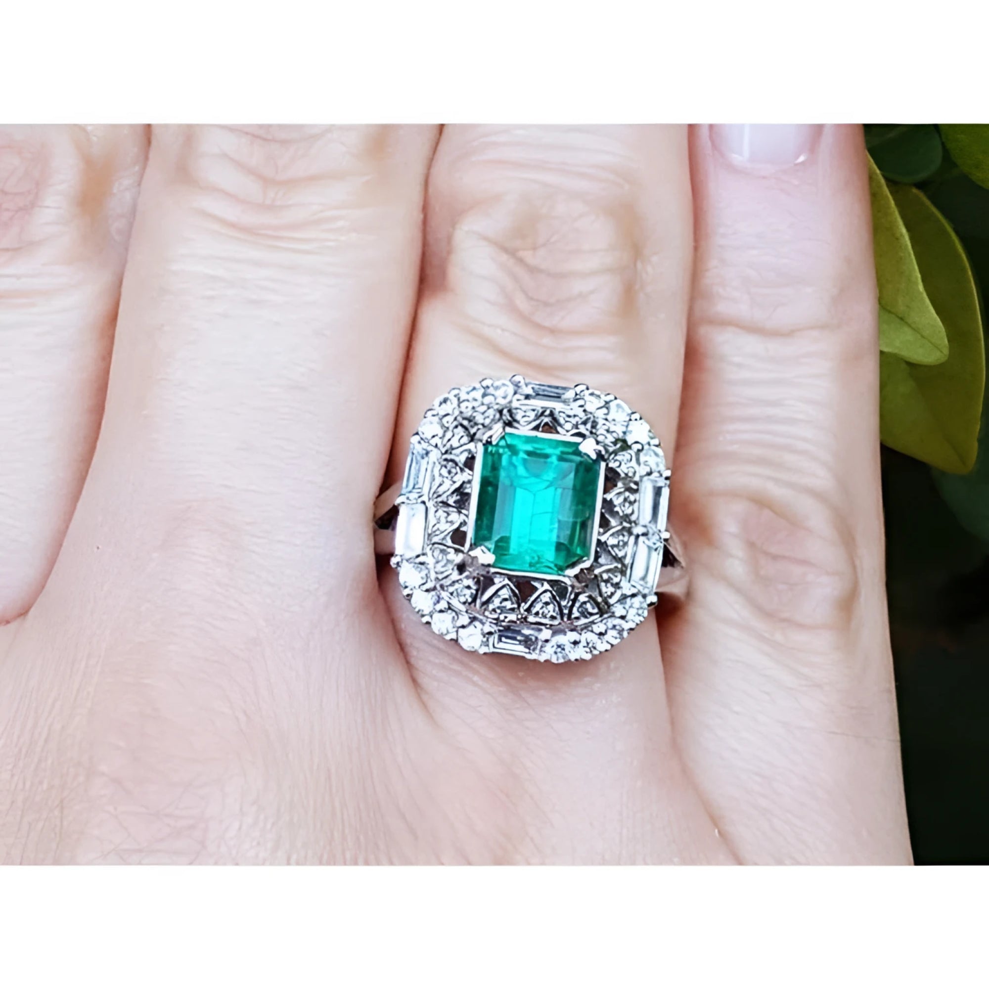 A vintage Colombian emerald ring with accent diamonds on a finger.