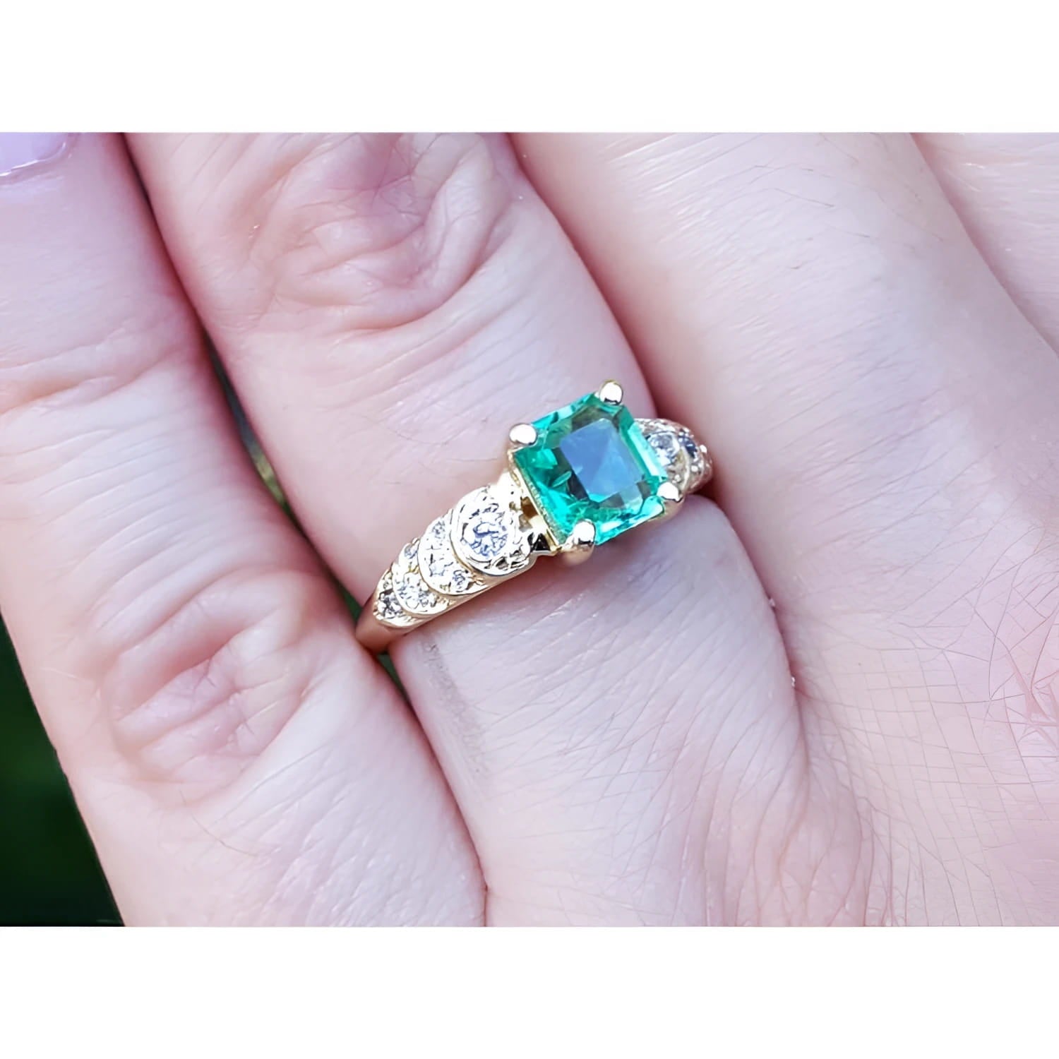 Vintage 14K yellow gold ring with a sparkling emerald-cut green emerald and accent diamonds on a finger.