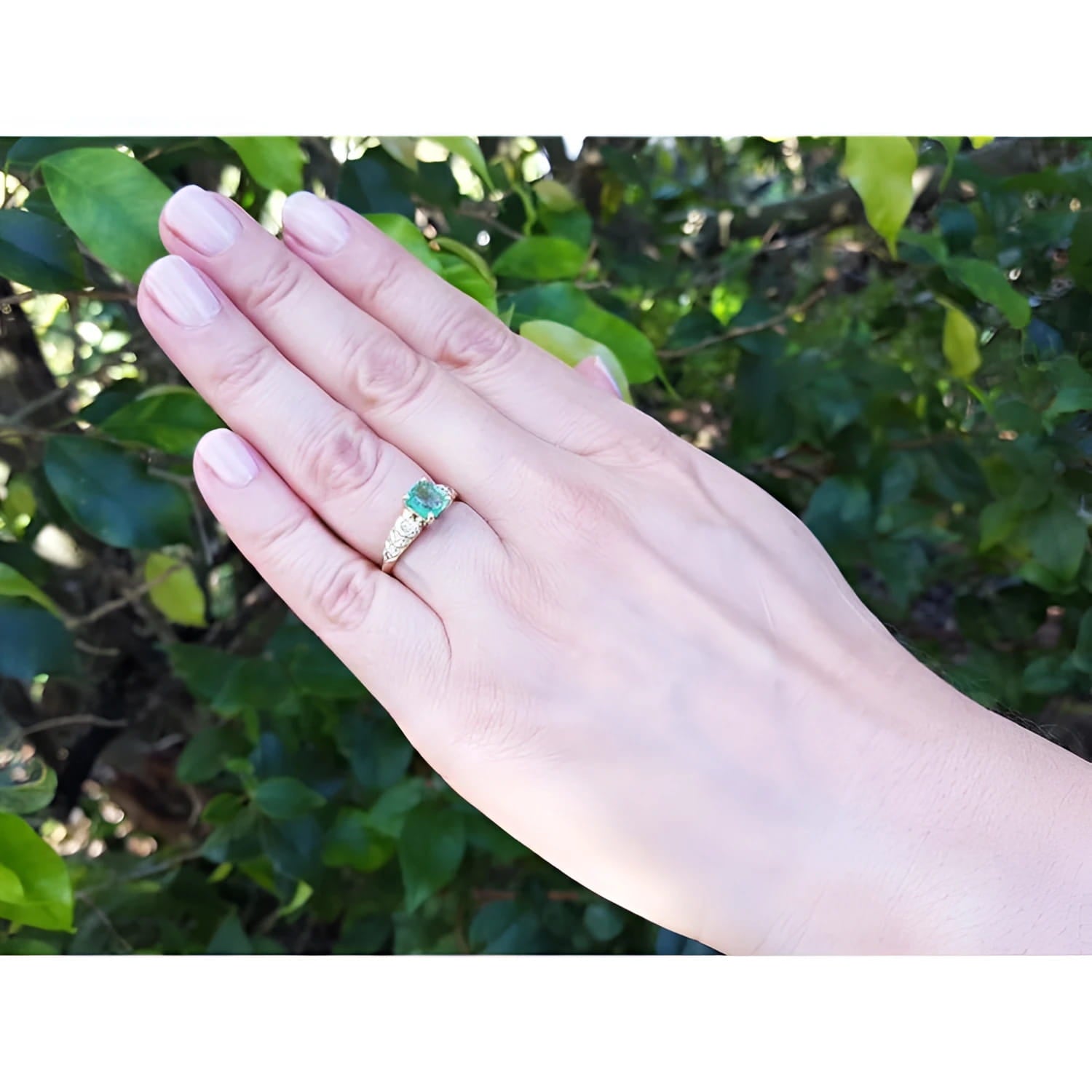 Vintage emerald and diamond ring in 14K yellow gold on a woman's hand.
