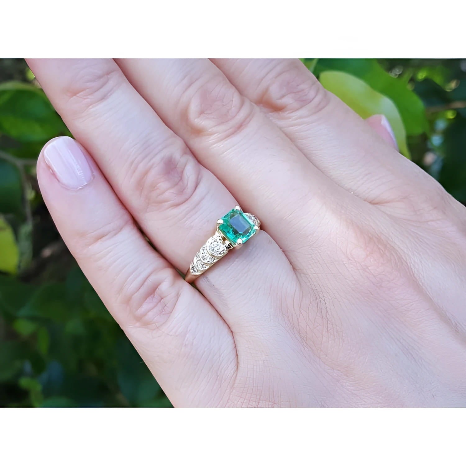Vintage 14K yellow gold ring with a sparkling emerald and natural diamond accents on a hand.