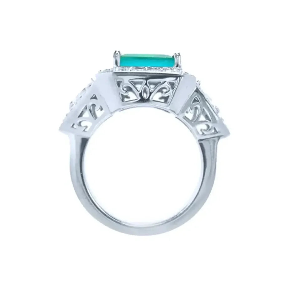 Anillo de oro blanco 18K con esmeralda colombiana rectangular y diamantes, diseño lateral calado.