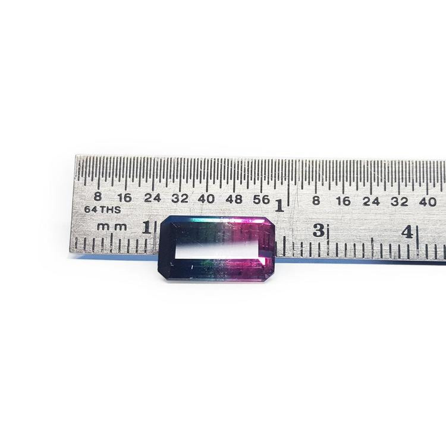 Rectangular emerald cut watermelon tourmaline with vibrant red-orange and deep blue-green colors, next to a ruler.