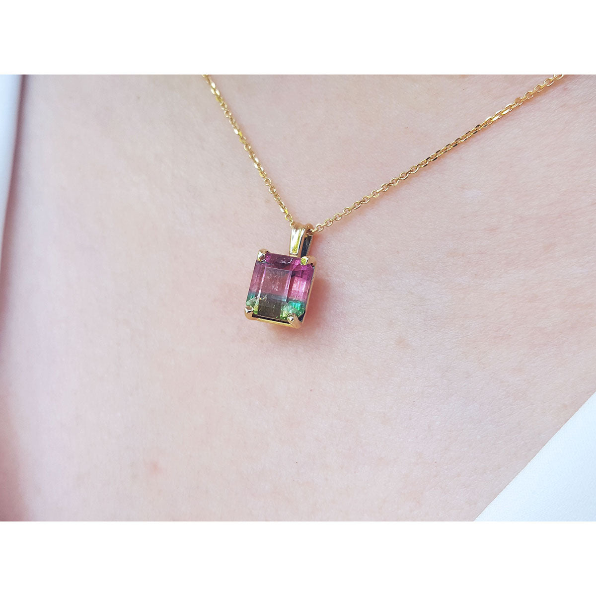 Necklace with a multicolored tourmaline gemstone pendant on a person's nek.