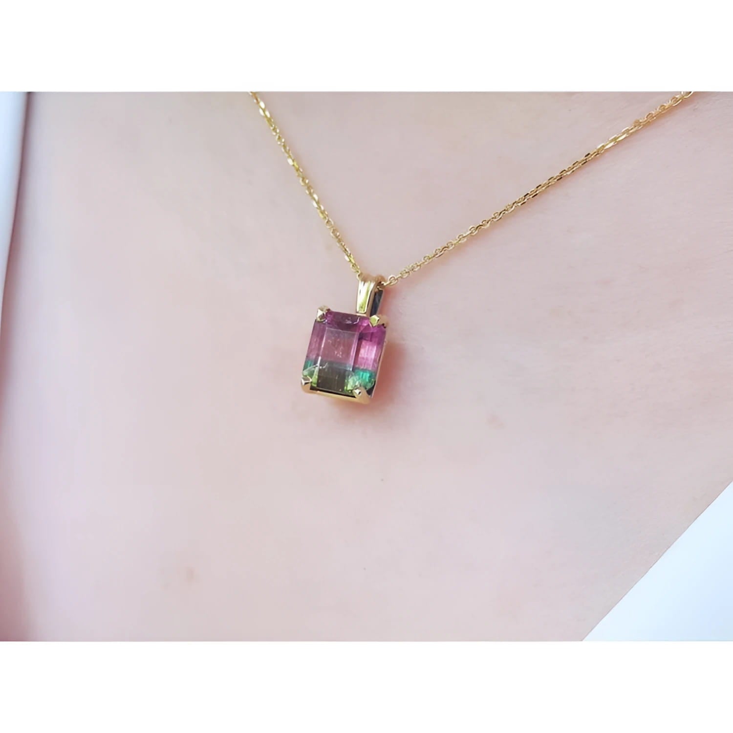 Brazilian bicolor tourmaline watermelon solitaire pendant in 14K yellow gold, worn on a neck.
