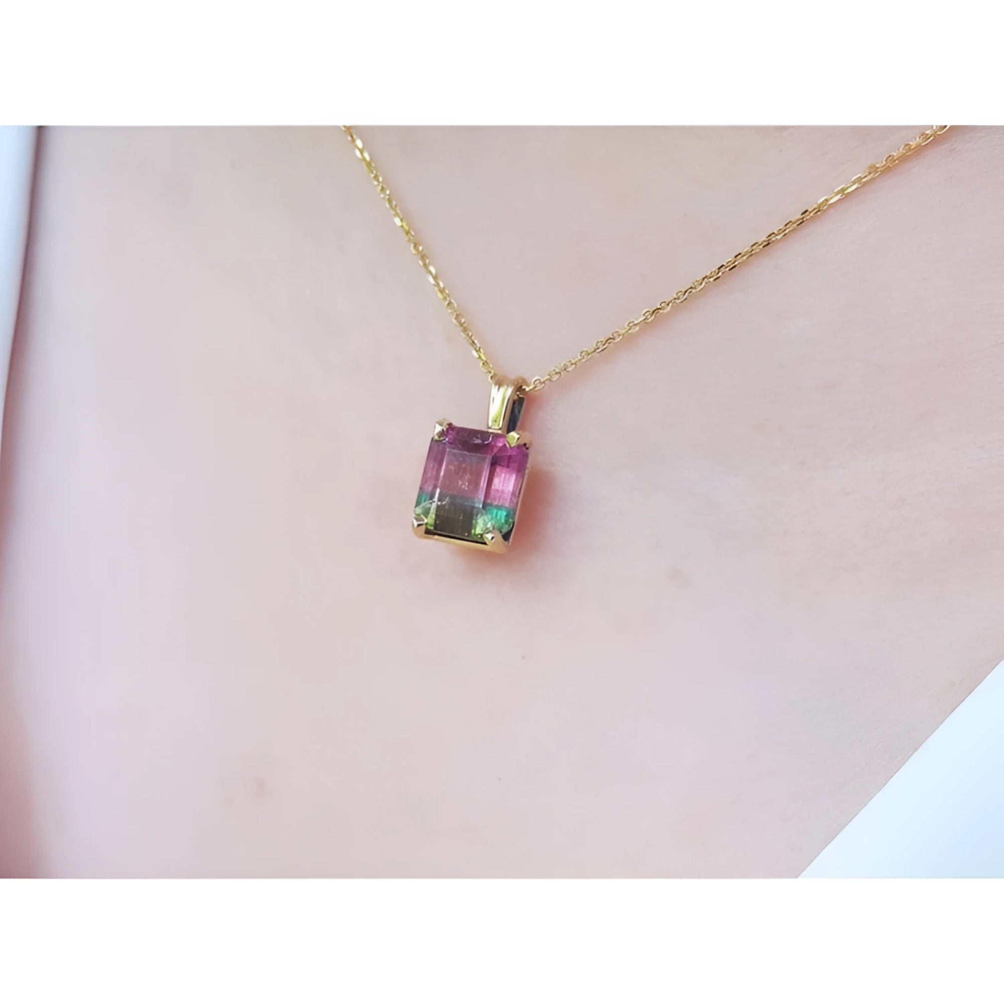 Brazilian bicolor tourmaline watermelon solitaire pendant in 14K yellow gold, worn on a neck.