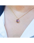 Necklace with a square tourmaline pendant worn by a person, against a neutral background.