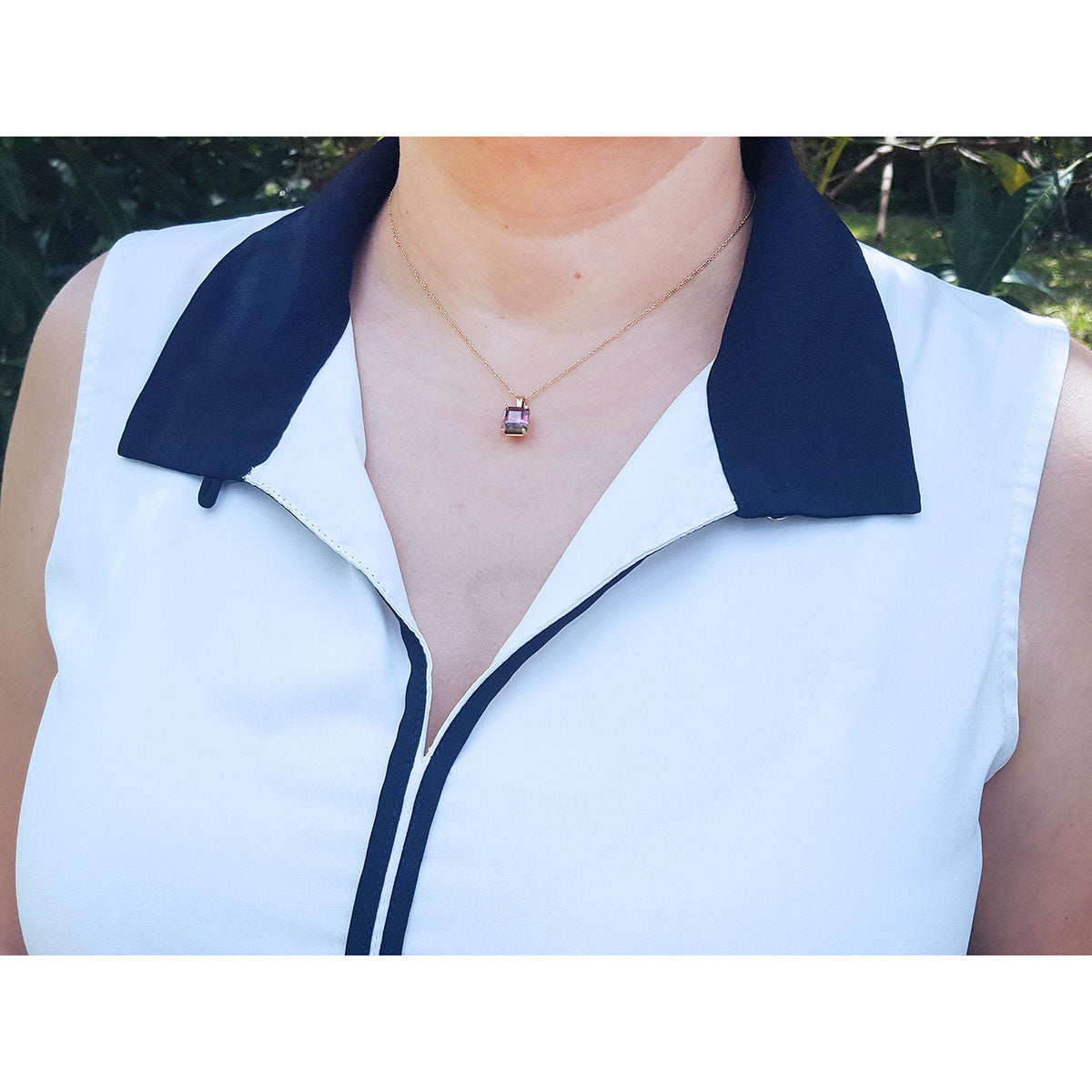 White sleeveless top with navy collar and zipper, worn by a person outdoors.