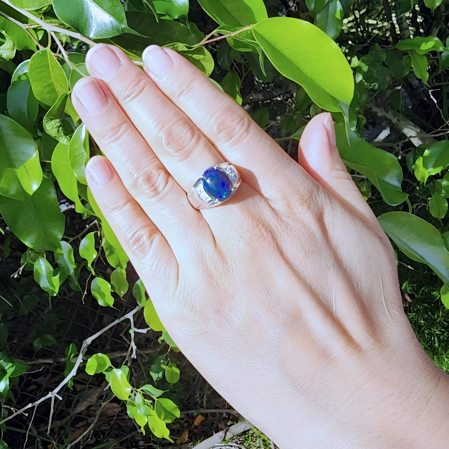 Men's sterling silver ring with a sparkling blue Welo black opal, accented by red and green flashes.