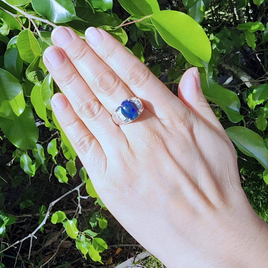 Men's sterling silver ring with a sparkling blue Welo black opal, accented by red and green flashes.