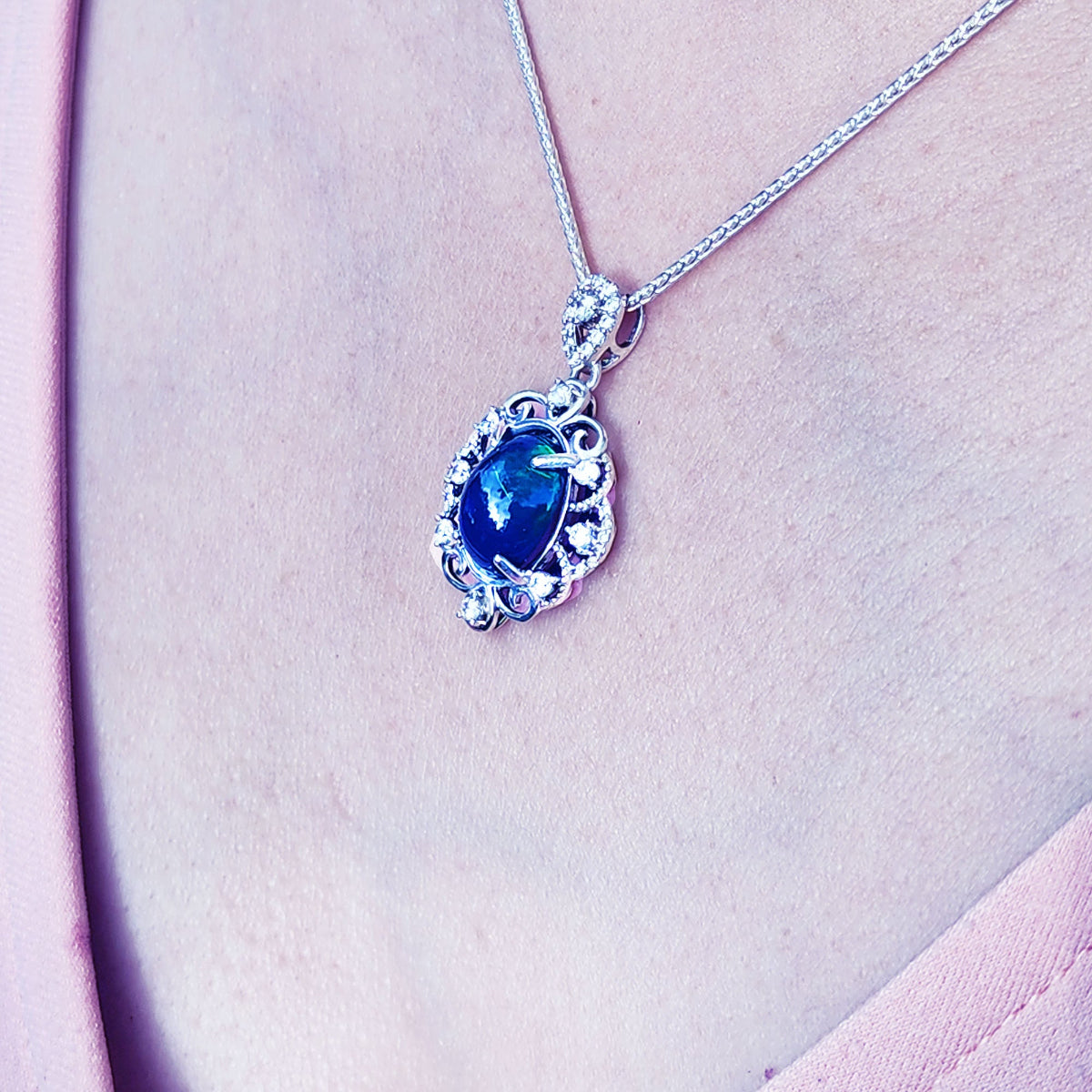 Silver necklace with a Ethiopian black opal pendant on a pink fabric background