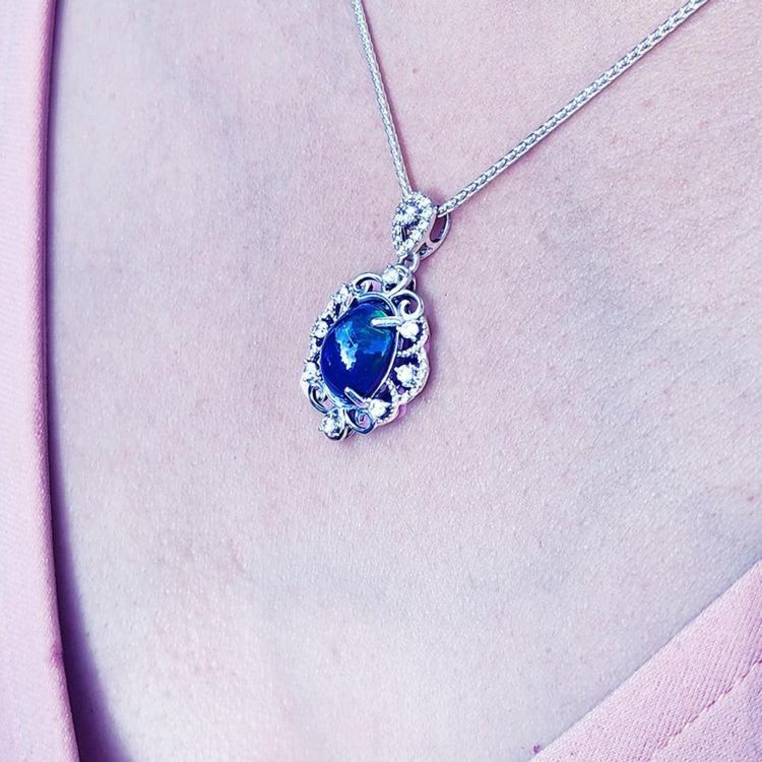 Multicolor Welo Ethiopian black opal pendant in ornate sterling silver with CZ accents on a silver chain.