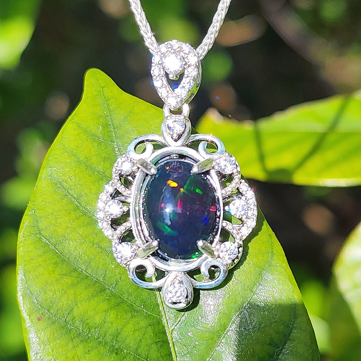 Silver pendant with a colorful Ethiopian black opal on a green leaf