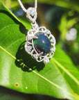 Opal pendant with silver frame on a green leaf