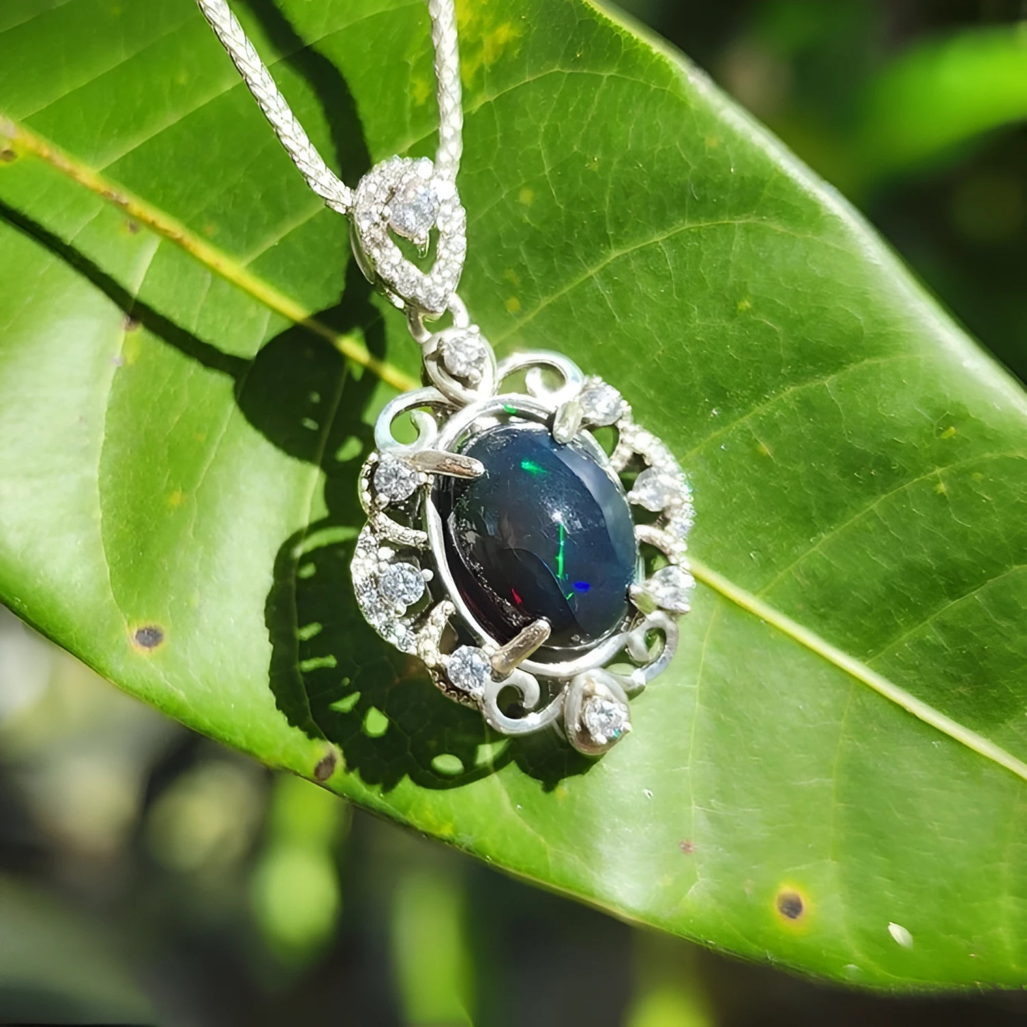 Multicolor Welo Ethiopian black opal pendant in sterling silver with CZ accents on a green leaf.
