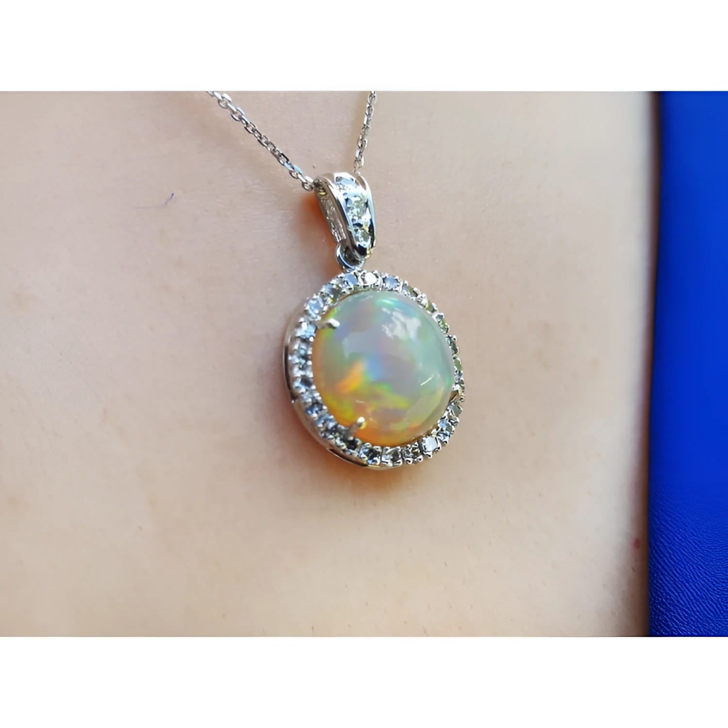 Ethiopian Welo opal pendant with red flashes, diamond halo, and 14K white gold chain on a person.