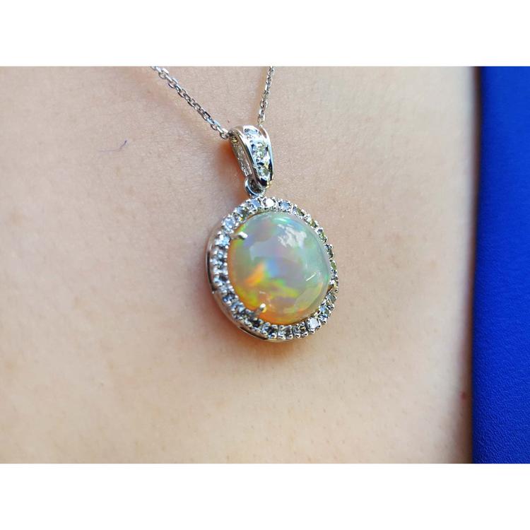 Ethiopian Welo opal pendant with red flashes, diamond halo, and 14K white gold chain on a person.
