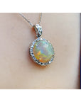 Ethiopian Welo opal pendant with red flashes, diamond halo, and 14K white gold chain on a person.