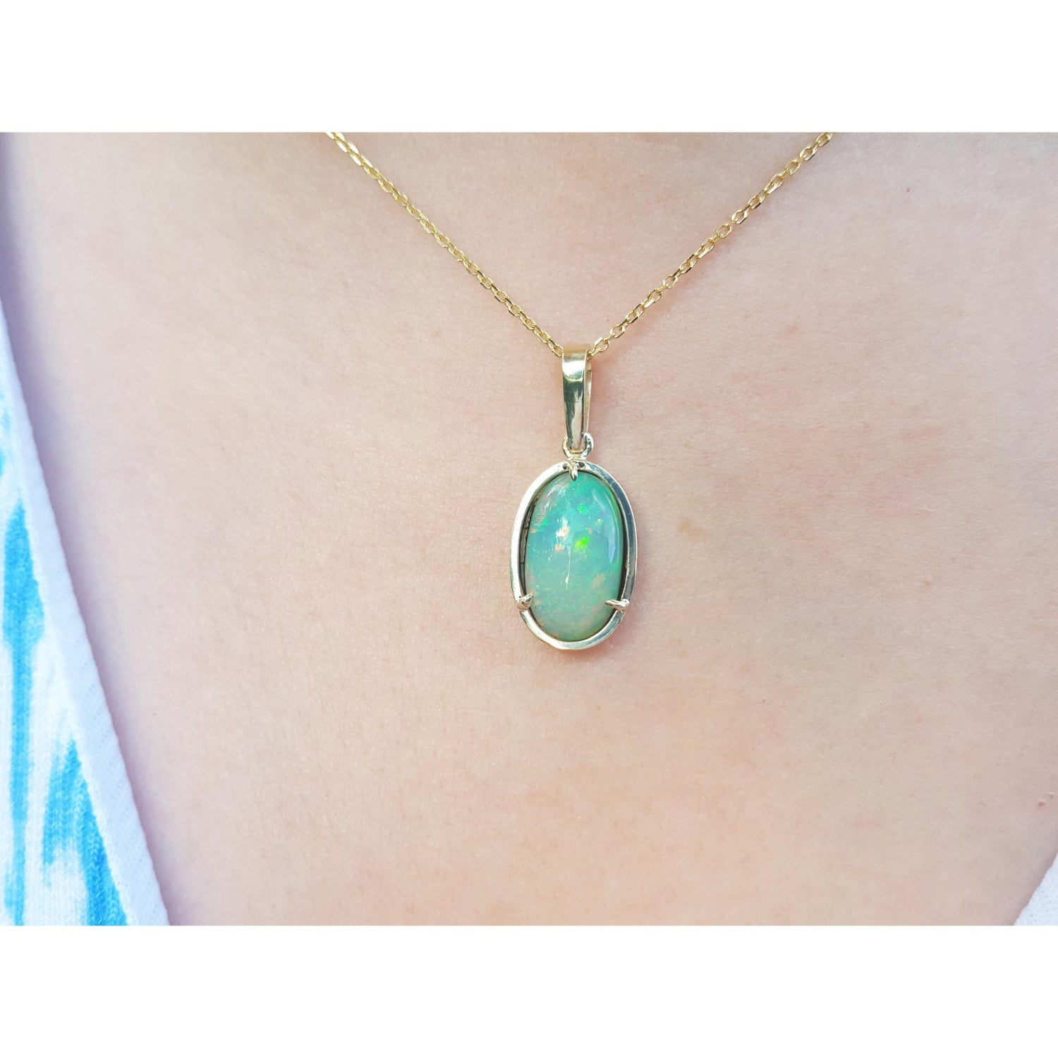 Opal pendant necklace on a person&#39;s neck with a blurred background
