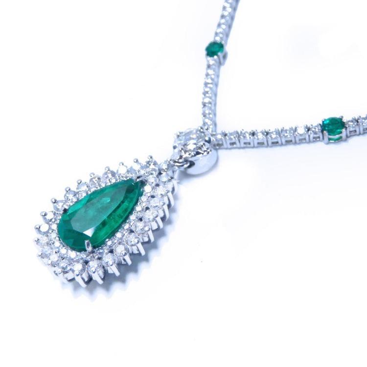 Right side of a diamond necklace with emerald pendant on a white background