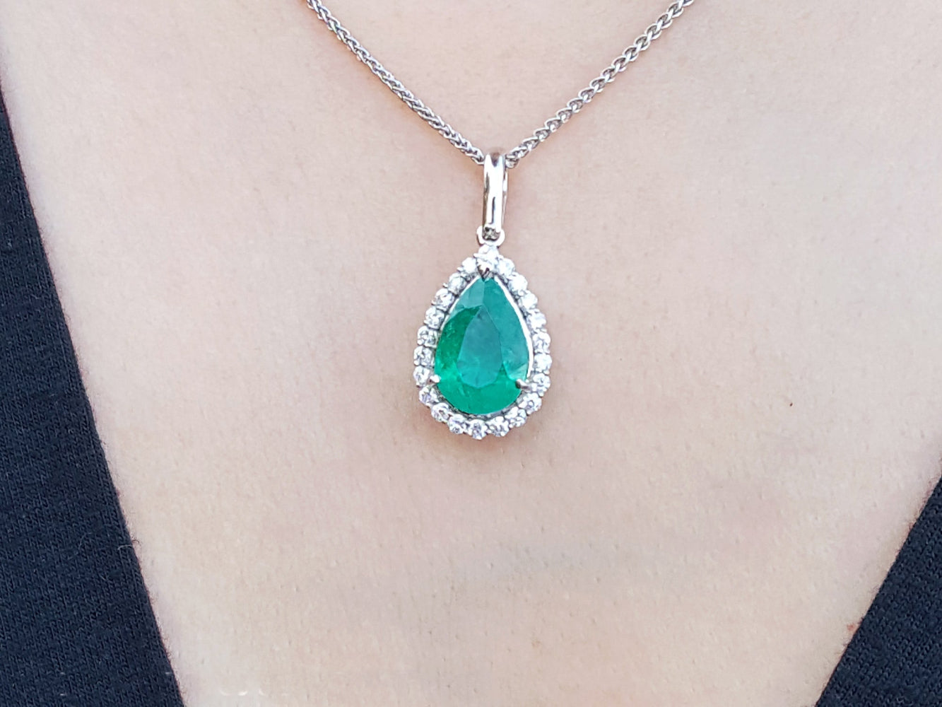 Emerald pendant necklace on a person wearing a black top