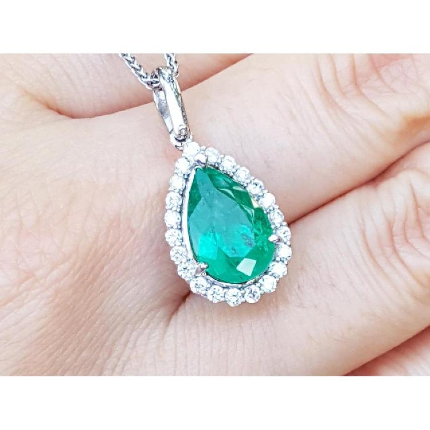 Pear-shaped deep green emerald pendant with diamond halo, set in 18K white gold.