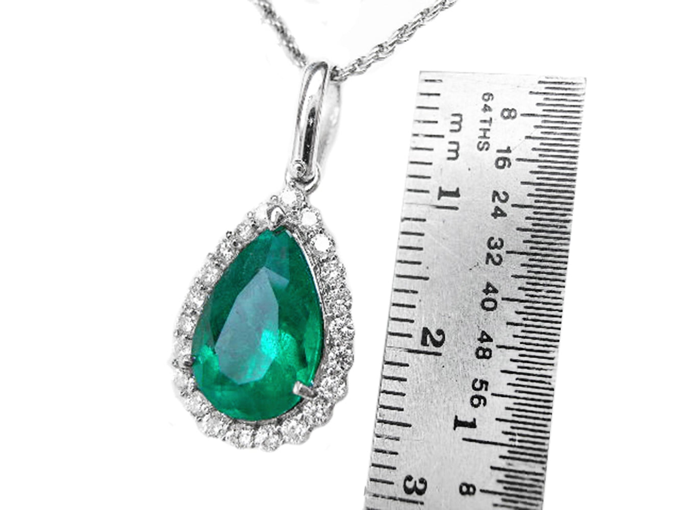 Emerald green teardrop pendant with chain next to a ruler for size reference