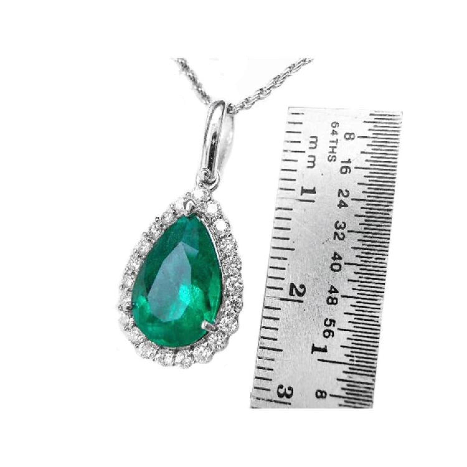 18K white gold pear-shaped emerald pendant with diamond halo, next to a ruler.