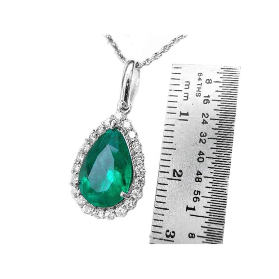 18K white gold pear-shaped emerald pendant with diamond halo, next to a ruler.