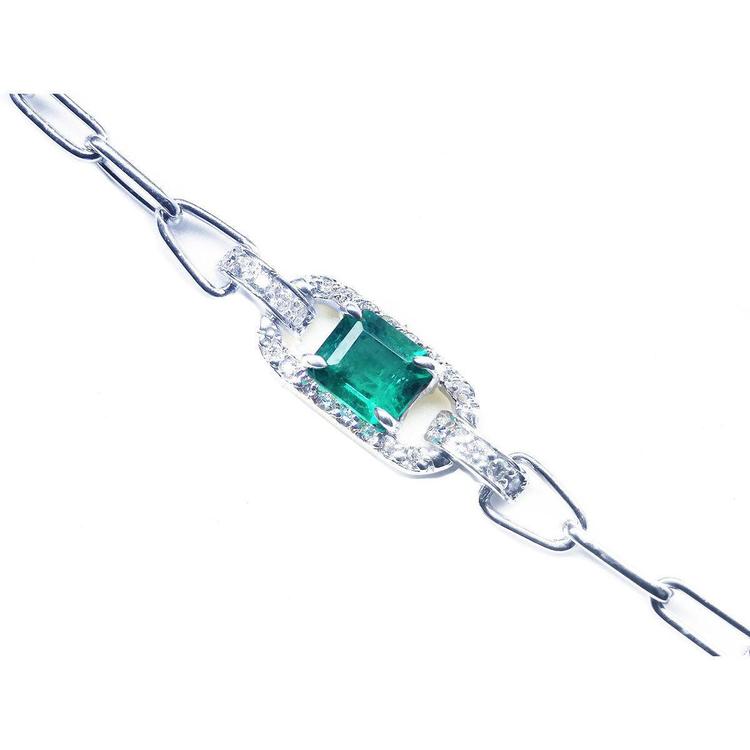 A 14k white gold paperclip bracelet with a natural colombian emerald and diamonds.