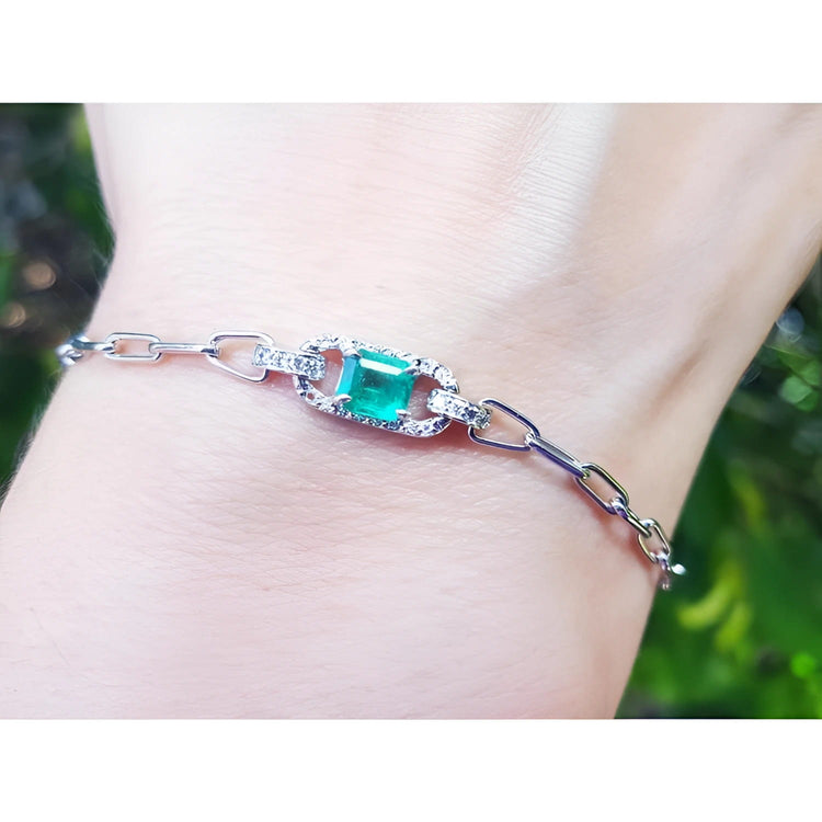 14K white gold paper clip bracelet with a rectangular bluish-green emerald and diamond halo on a wrist.