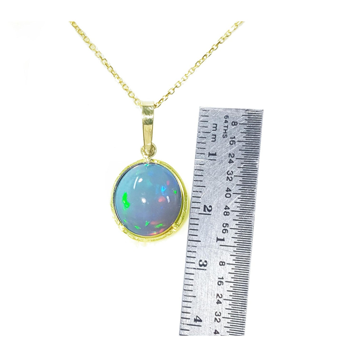Opal pendant necklace with gold chain next to a ruler for scale on a white background.