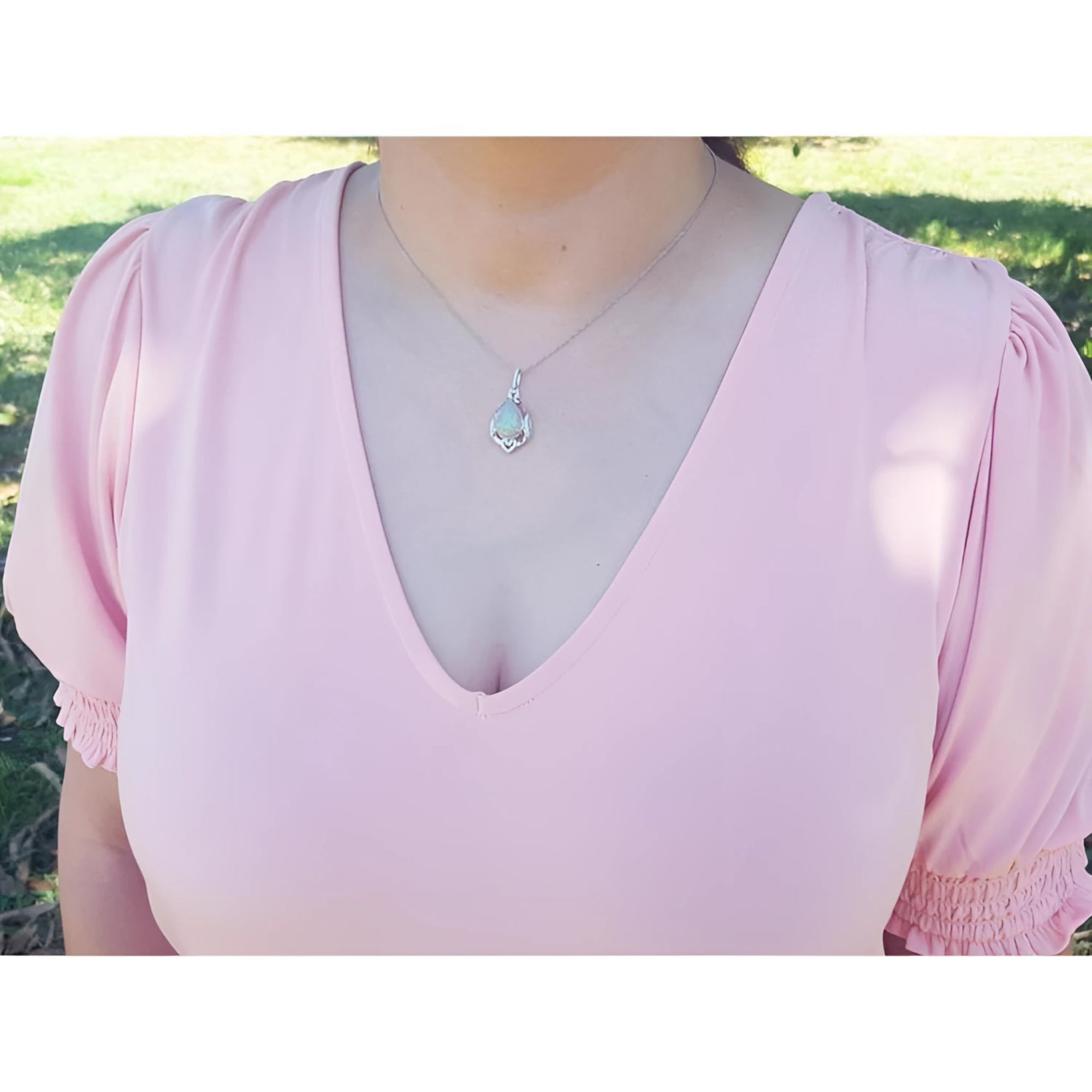 Pear-shaped Welo Ethiopian opal pendant in sterling silver with cubic zirconia, worn on a pink top.