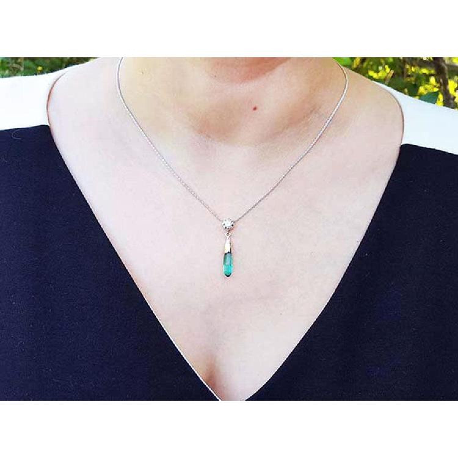 Colombian emerald briolette necklace with a diamond slider on a 14K white gold chain, worn on a person.