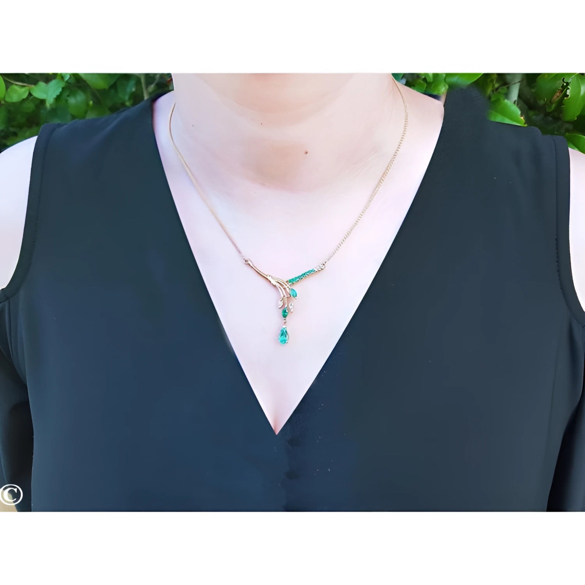 14K yellow gold necklace with marquise and pear-shaped Colombian emeralds and diamonds on a woman's neck.